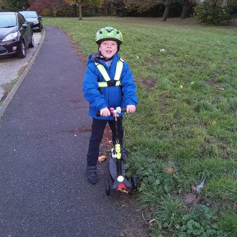 Child on their way to school on scooter wearing highvis